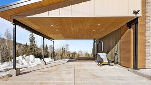 A covered outdoor area with a concrete floor, a covered walkway, and a snow-covered landscape in the background. - Summer Getaway | Pool Table, Foosball & Views (Brian Head)