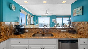Une cuisine avec des murs de couleur turquoise, un plan de travail en granit, un évier à deux bacs et un lave-vaisselle.