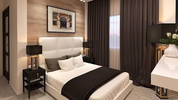 A modern hotel room with a large bed, two bedside tables, a desk, and a painting on the wall. - Harrington Inn  (Ibadan)