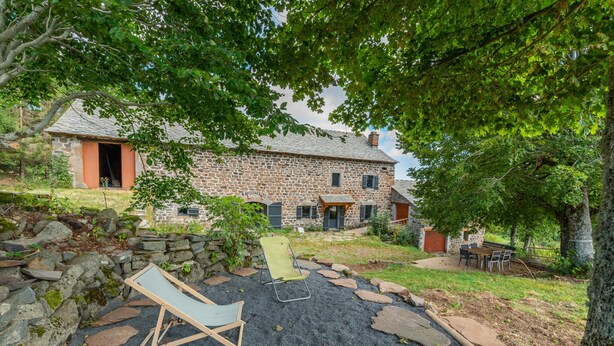 A stone house with a gravel patio, a wooden deck, and a lawn. - Typical renovated farmhouse - Ideal for a family getaway (Champclause)