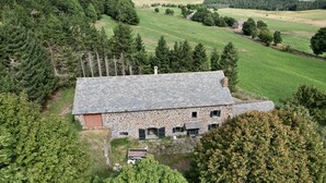 A stone building with a sloped roof, surrounded by dense trees and open fields. - Typical renovated farmhouse - Ideal for a family getaway (Champclause)