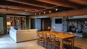 A cozy living room with a wooden dining table, a sofa, and a fireplace. - Typical renovated farmhouse - Ideal for a family getaway (Champclause)