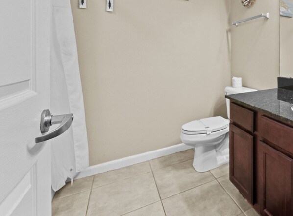 Een badkamer met toilet, wastafel en douchegordijn.