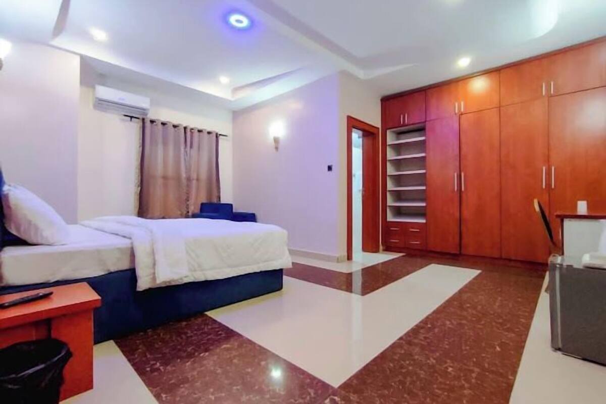A bedroom with a bed, a desk, a wardrobe, and a bathroom.