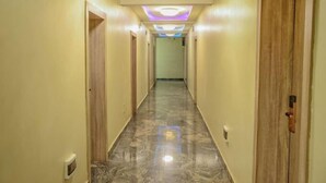 A hotel hallway with marble flooring, wooden doors, and a ceiling with recessed lighting. - E- Exclusive Hotel  (Ibadan)