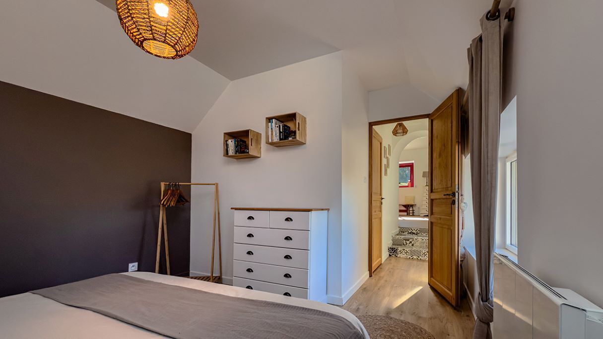 A bedroom with a bed, a dresser, a wardrobe, and a hanging light fixture.