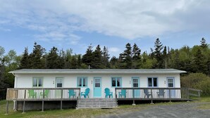 A single-story cabin with a porch and outdoor seating. - Buoy & Arrow Restaurant and Suites (Rocky Harbour)