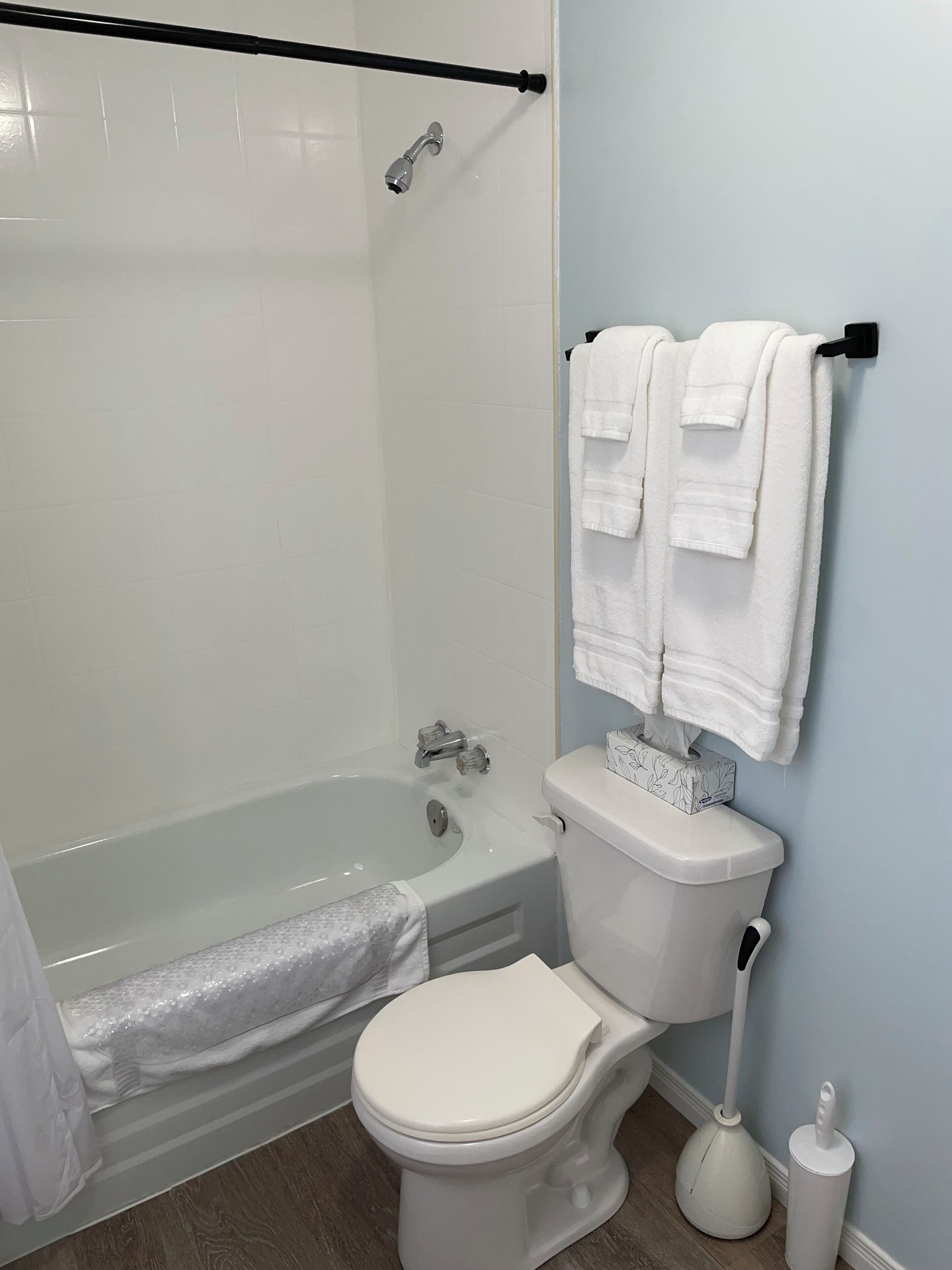 A bathroom with a bathtub, toilet, and a towel rack.