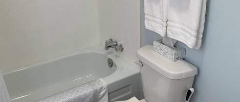 A bathroom with a bathtub, toilet, and a towel rack.