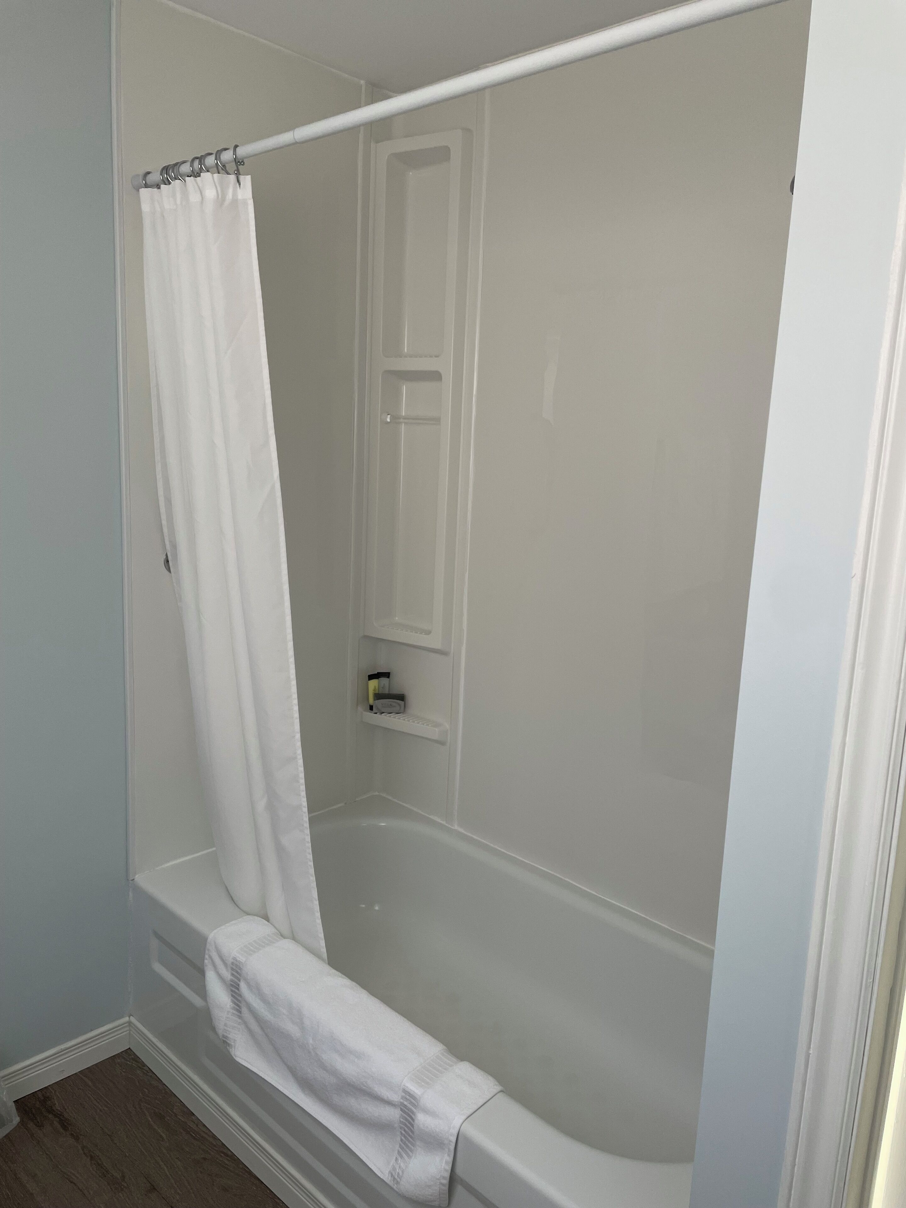 Une salle de bain avec une baignoire, un rideau de douche et une étagère contenant des articles de toilette.