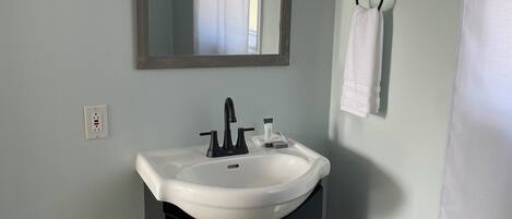 A bathroom with a white sink, black cabinets, a mirror, and a towel ring.