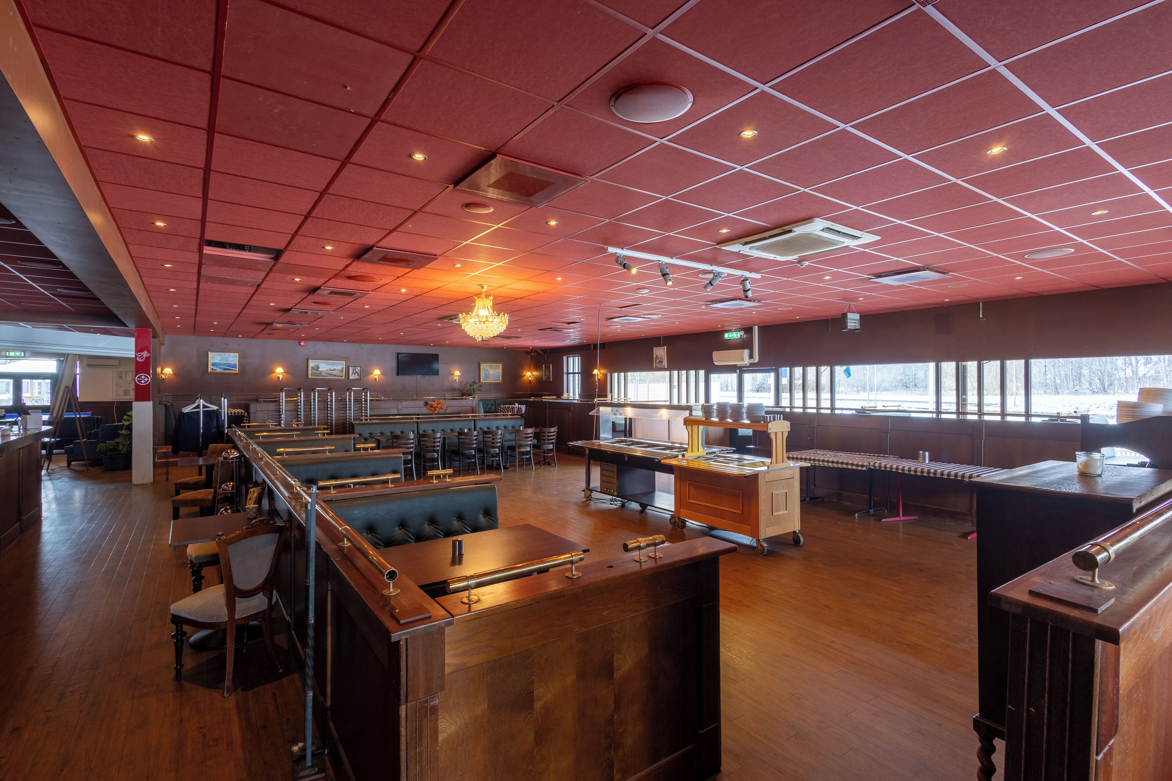 Un restaurante espacioso con techo alto, suelo de madera y una zona de bar.