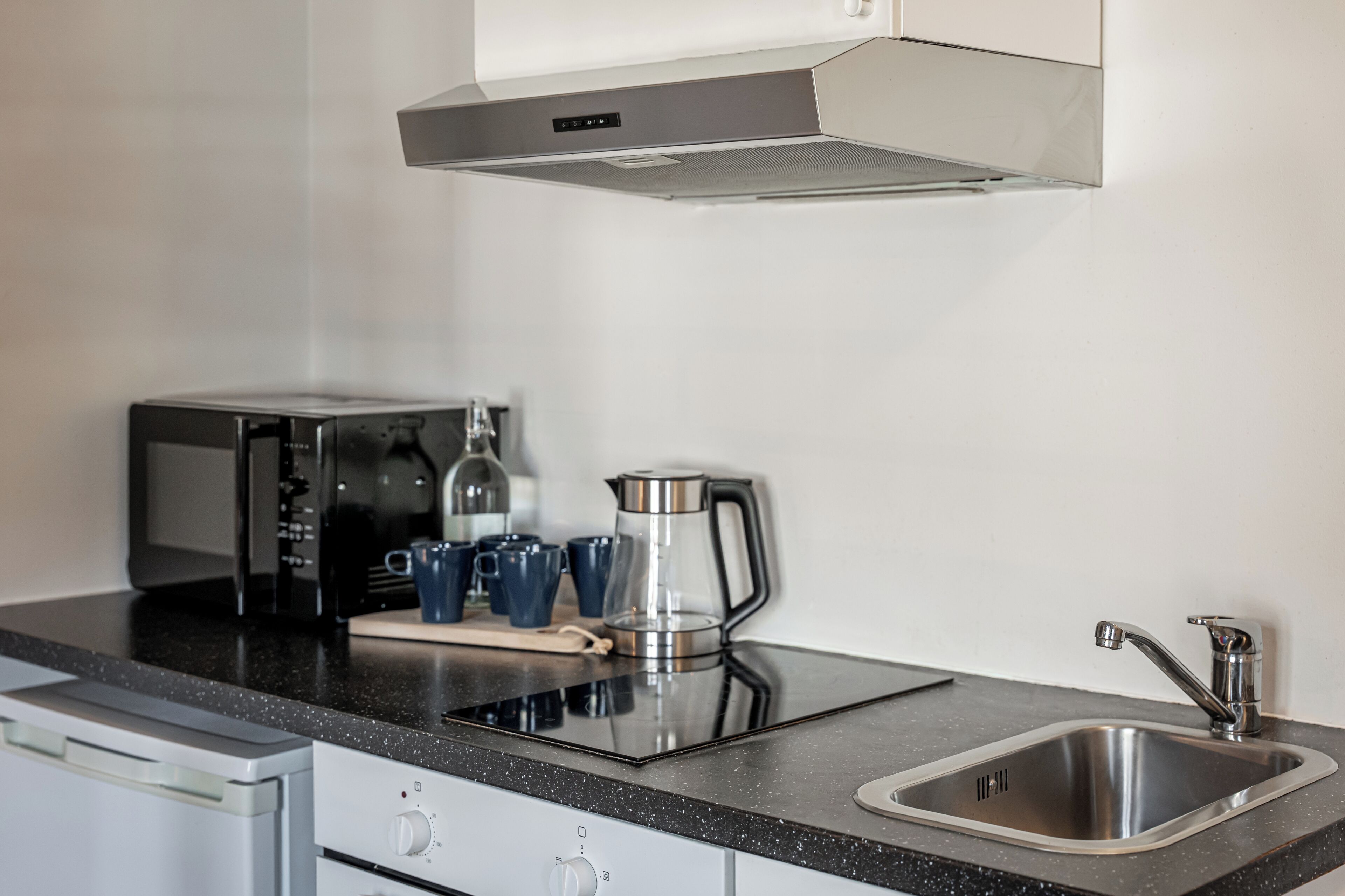Una cocina con un lavamanos de acero inoxidable, una cafetera y un tostador.