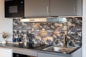 Una cocina moderna con protector contra salpicaduras de piedra, electrodomésticos de acero inoxidable y un microondas integrado.