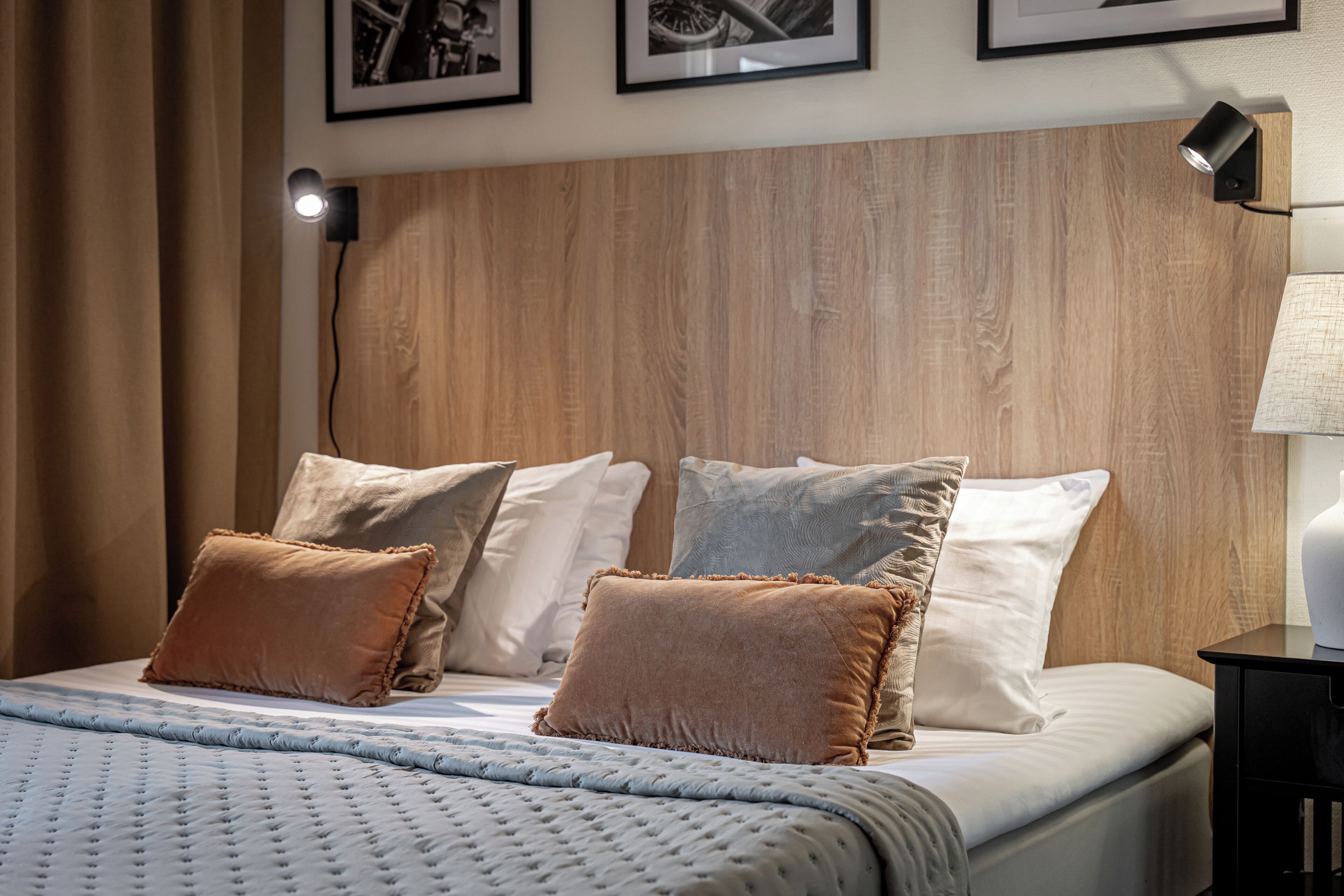 A neatly made bed with a textured duvet, a wooden headboard, and multiple pillows.