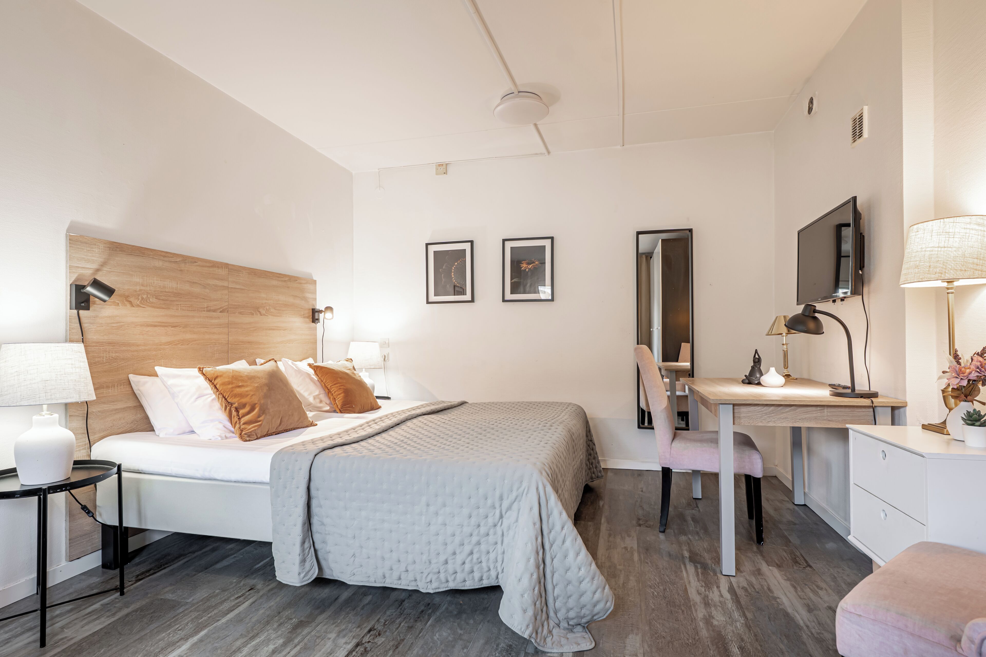 A modern bedroom with a bed, desk, chair, and a mirror.