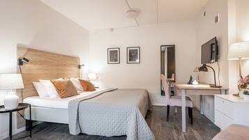 A modern bedroom with a bed, desk, chair, and a mirror.