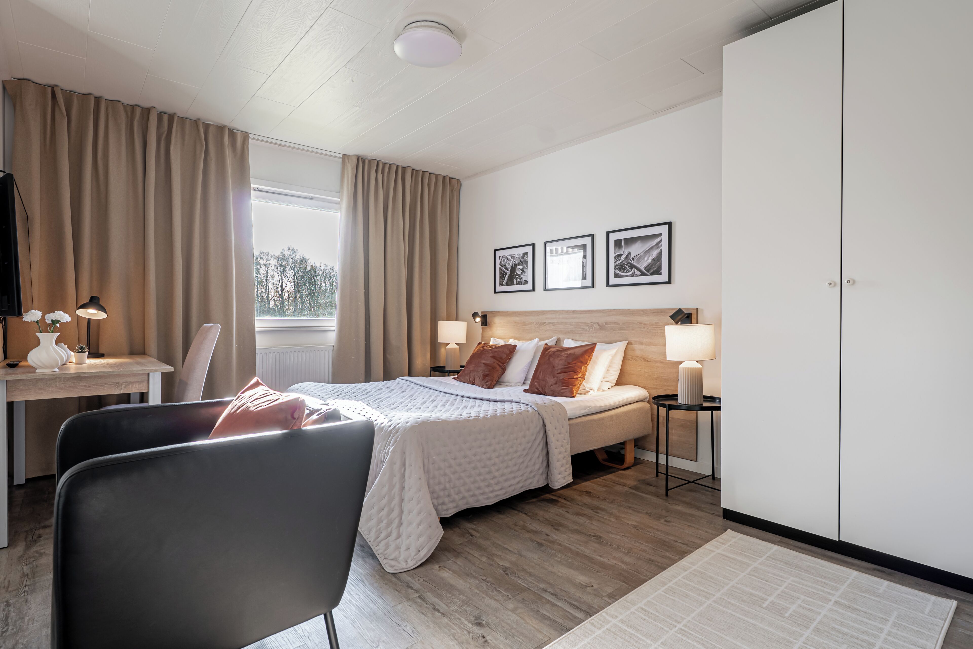 Una habitación de hotel con cama, mesitas de noche, escritorio, silla y armario.