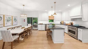 A spacious kitchen with white cabinetry, a central island, and pendant lighting.