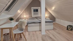 A cozy attic bedroom with a sloped ceiling, a bed, a desk, and a chair. - ***SANDLOFT*** (Sankt Peter-Ording)