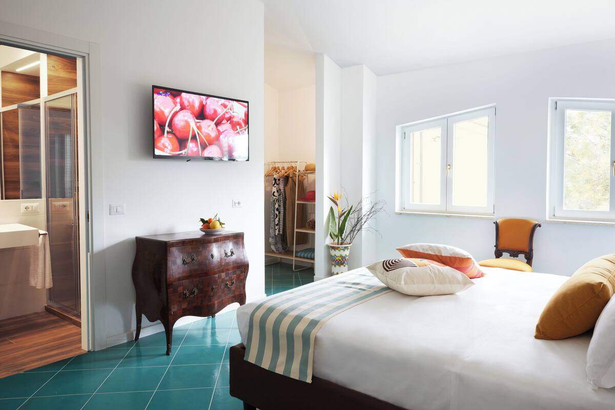 A bedroom with a bed, a dresser, a television, and a closet.