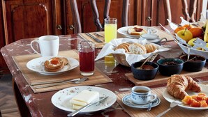 Uma mesa de café da manhã posta com diversos alimentos, incluindo doces, frutas e bebidas.