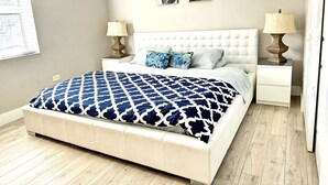 A bedroom with a large bed, two bedside tables, and two wall-mounted lamps. - House with Hot Tub, 10 mins to the Beach (Miami)