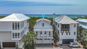 A coastal residential area with white houses, a clear view of the ocean, and a blue location pin.