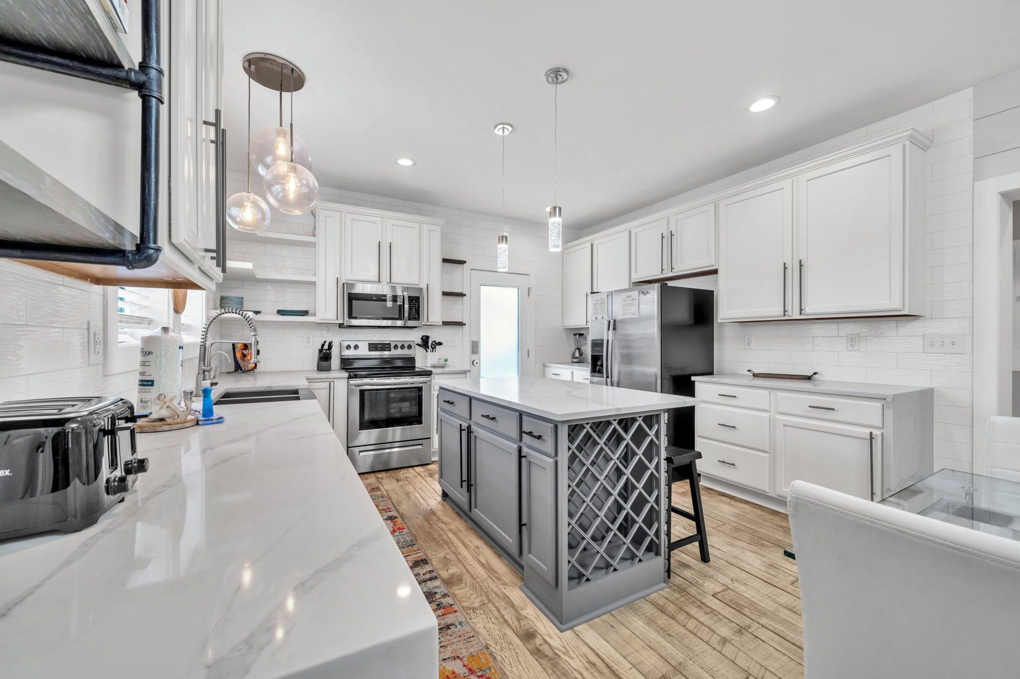 A modern kitchen with white cabinetry, stainless steel appliances, and a central island.