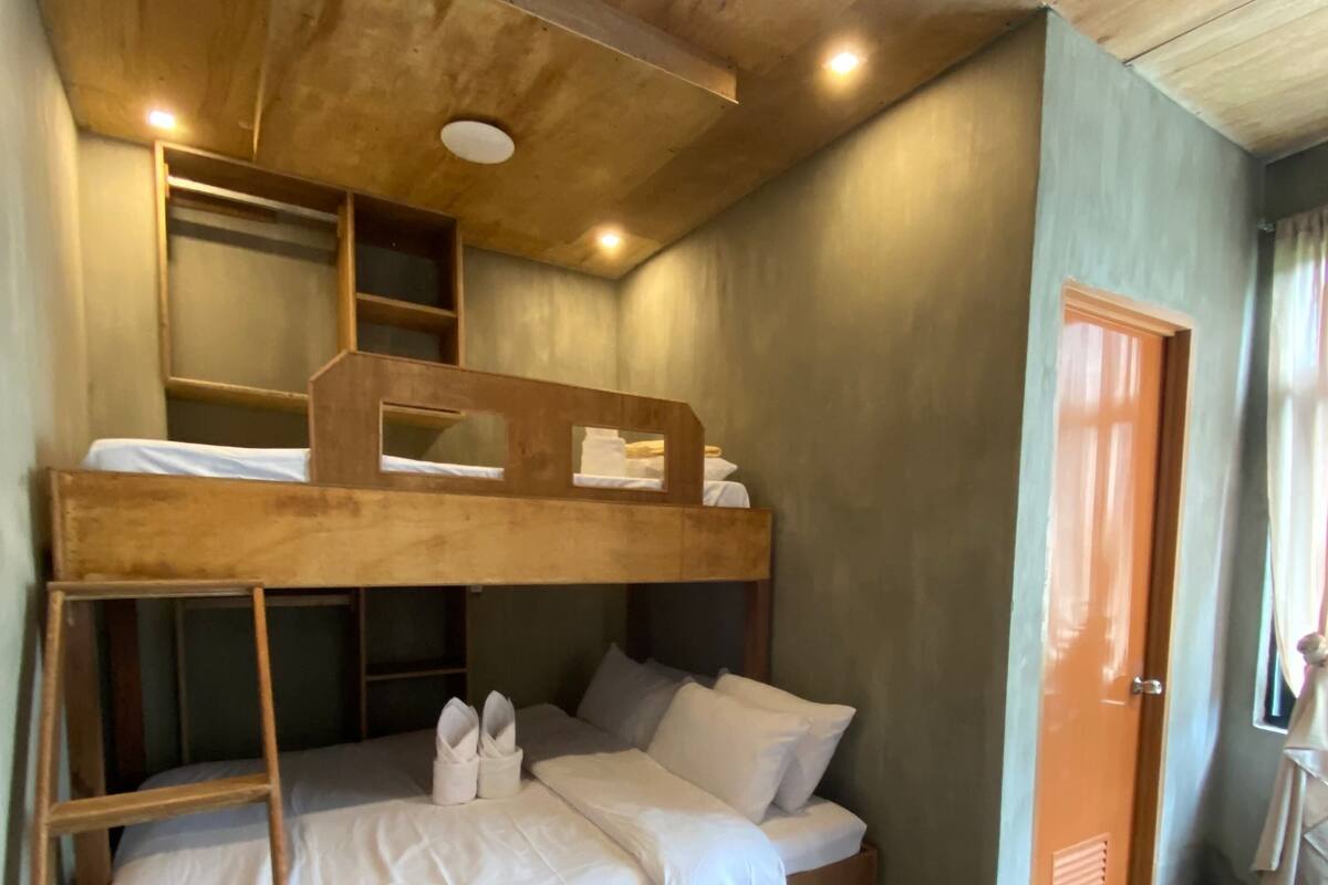A bunk bed with a ladder, white bedding, and a stone floor.