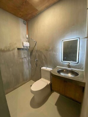 Une petite salle de bain comprenant des toilettes, un lavabo et une douche.