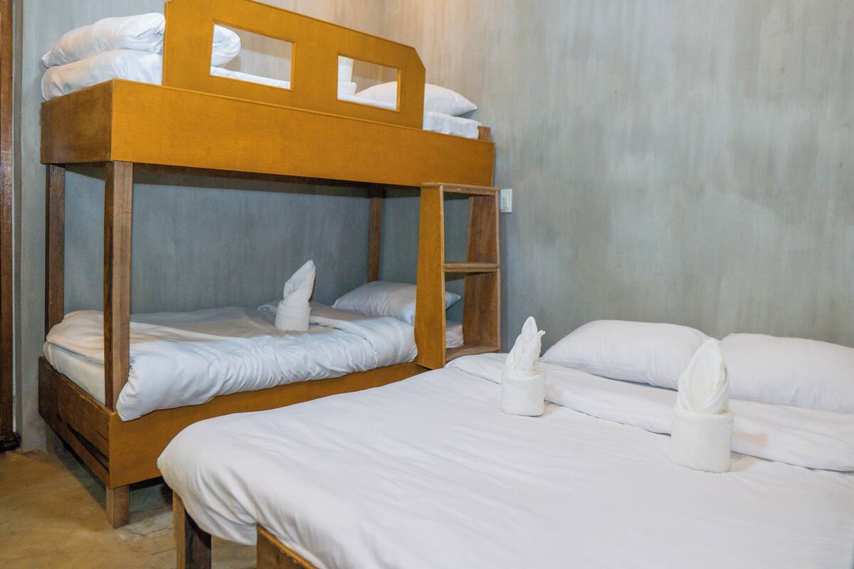 A bunk bed room with white bedding and a wooden headboard.