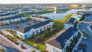 A residential area with colorful houses, a lake, and a parking lot. - Kid-Friendly, themed vacation home close to Disney/Universal (Kissimmee)