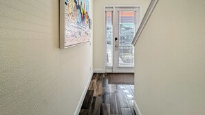 A hallway with a wooden floor, a door with blinds, and a painting on the wall. - Kid-Friendly, themed vacation home close to Disney/Universal (Kissimmee)
