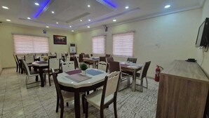 A conference room with multiple tables and chairs, equipped with ceiling lights and air conditioning. - Habitat Suites and Apartments (Lagos)