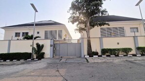 A gated residential area with two houses, a paved driveway, and a tree. - Habitat Suites and Apartments (Lagos)