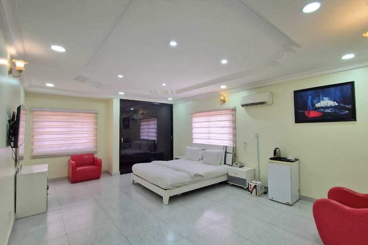 A bedroom with a bed, a desk, a chair, and a TV.