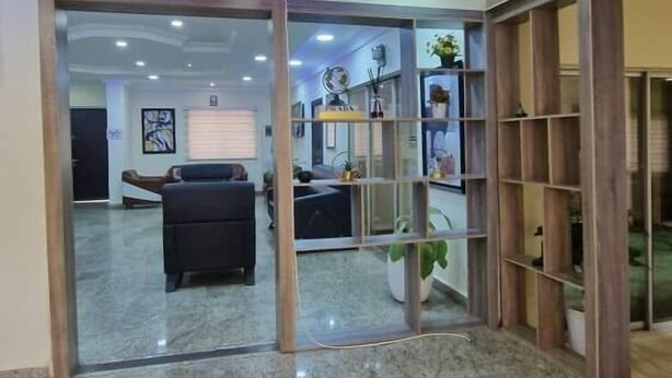 A lobby with a marble floor, a reception desk, and a seating area. - Habitat Suites and Apartments (Lagos)