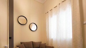 Quarto com uma cama, dois espelhos na parede e uma janela com cortinas.