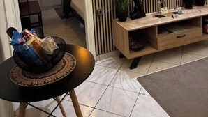 Uma sala de estar moderna com uma televisão de tela plana fixada na parede, um móvel para entretenimento de madeira e uma pequena mesa com um saco de lanches.