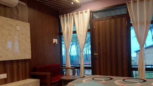 Une chambre d’hôtel avec un lit, une banquette, une petite table et une vue sur l’extérieur.