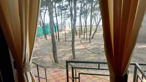 Une vue depuis un balcon doté d’une balustrade, avec une pelouse verdoyante et des arbres en arrière-plan.