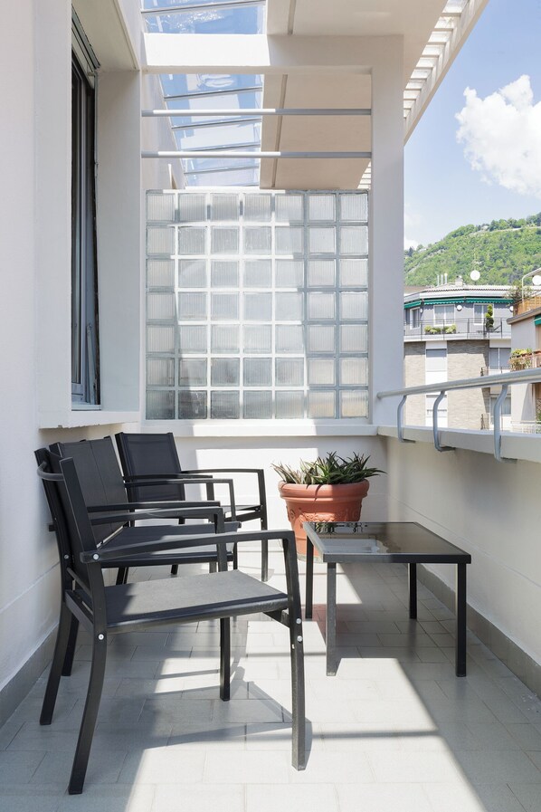Un balcon doté d’un espace salon, d’une plante en pot et offrant une vue sur une colline.