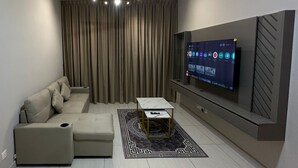 A modern living room with a sofa, ottoman, coffee table, TV, and a ceiling fan. - 1-bedroom apartment in marvelous Kuala Lumpur with free WiFi + Netflix (Wilayah Persekutuan)