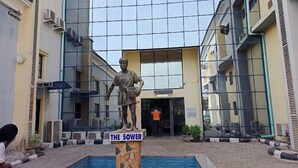 A statue labeled "THE SOWER" in front of a modern building with a glass facade.
