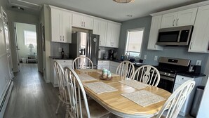 Una cocina amplia con armarios blancos, una mesa de comedor de madera y una lámpara colgante.