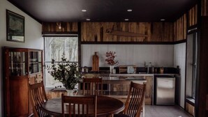Una cocina moderna con armarios de madera, una isla central y un comedor con mesa y sillas redondas.