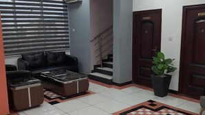 A lobby with a black leather sofa, a marble coffee table, a potted plant, and a staircase. - Dominion City Guest House (Ibadan)