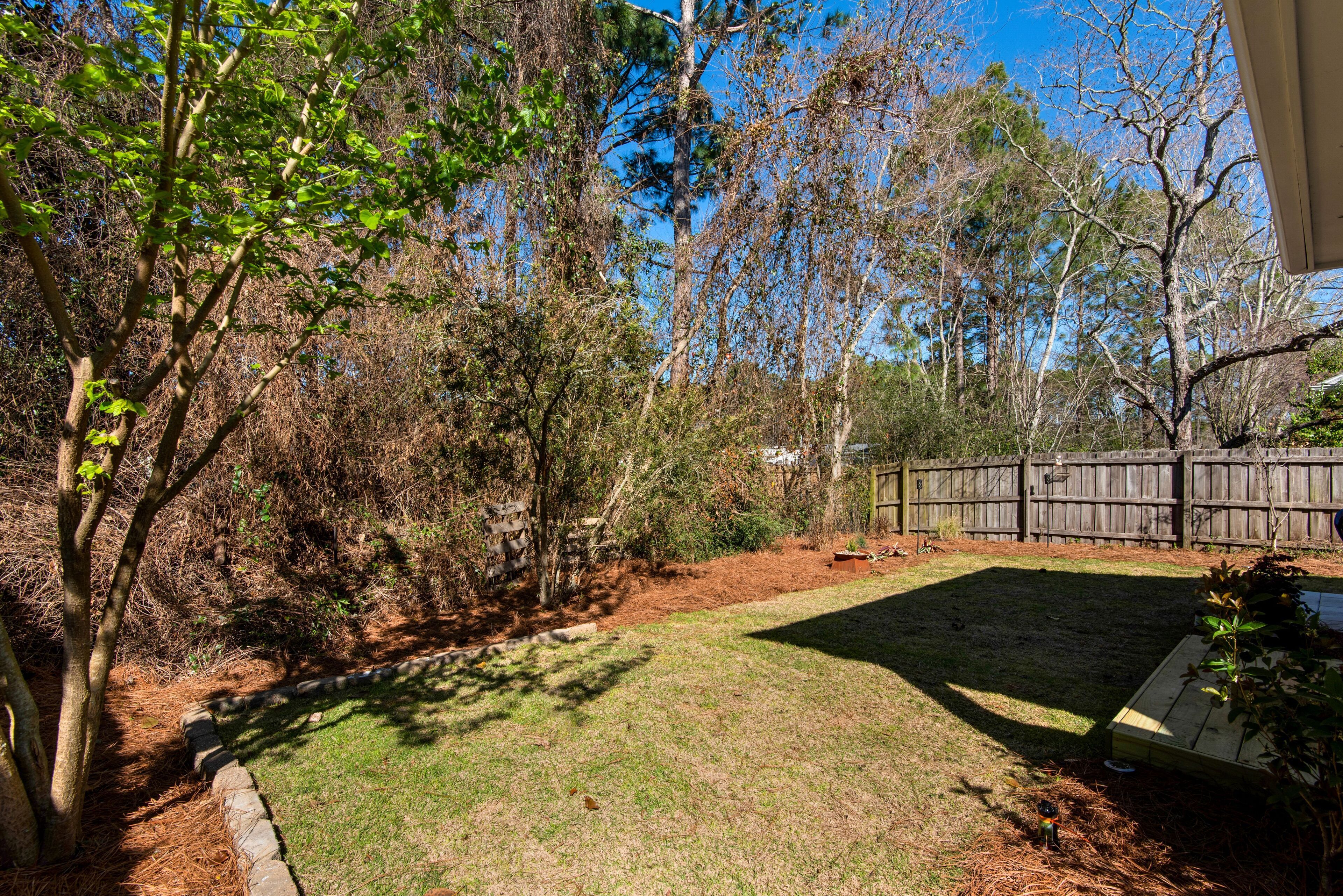 A backyard with a wooden deck, a stone border, and a grassy area.