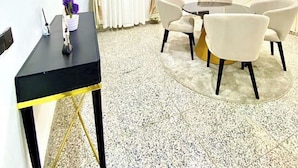 Una sala de estar moderna con una mesa redonda, cuatro sillas, una mesita auxiliar negra y un jarrón decorativo.